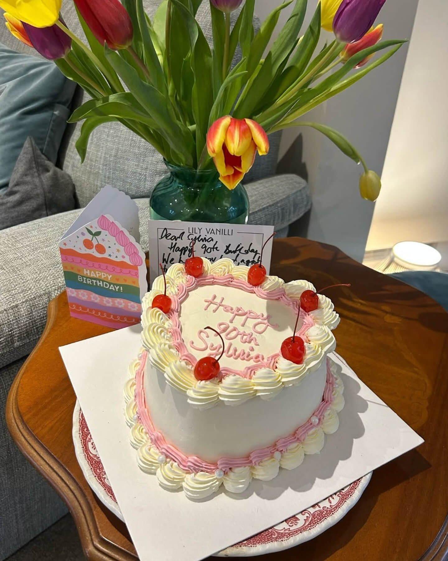 a heart shaped cake on a table with a vase of flowers